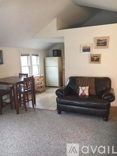 A living room with a black couch and a wooden dining table.