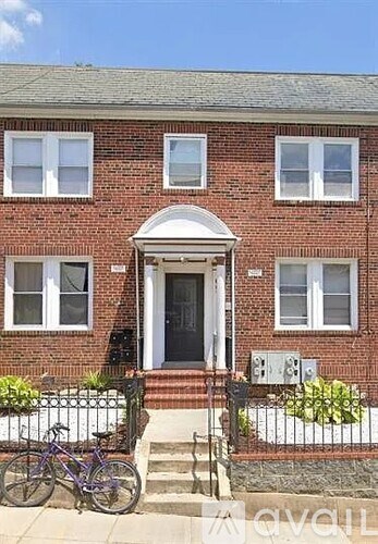 A brick house with a black door and a bicycle in front.