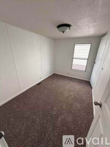 A room with a carpeted floor and a window with blinds.