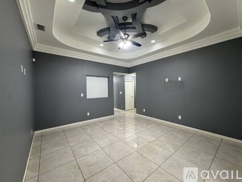 A spacious room with a ceiling fan and tiled flooring.