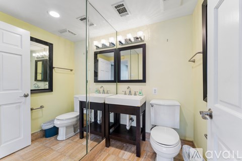 A bathroom with a toilet, sink, and mirror.