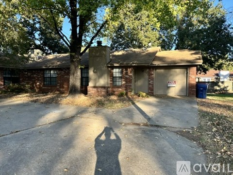A house with a driveway and a tree in front.