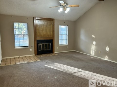 A spacious living room with a fireplace and a ceiling fan.