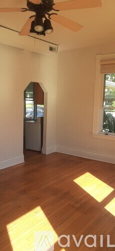 A room with a ceiling fan and wooden flooring.