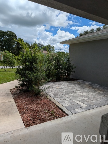 A patio area with a grey tiled floor and a small tree in the middle.