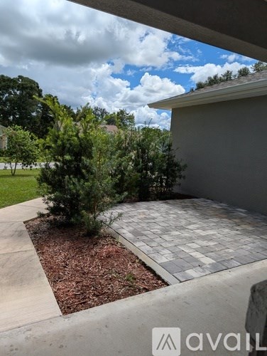 A patio area with a grey tiled floor and a small tree in the middle.
