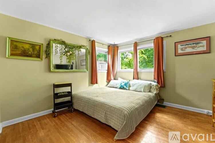 A bedroom with a bed, a mirror, and two pictures on the wall.