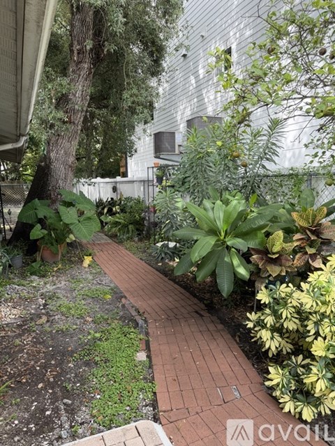 A garden with a brick pathway and green plants.