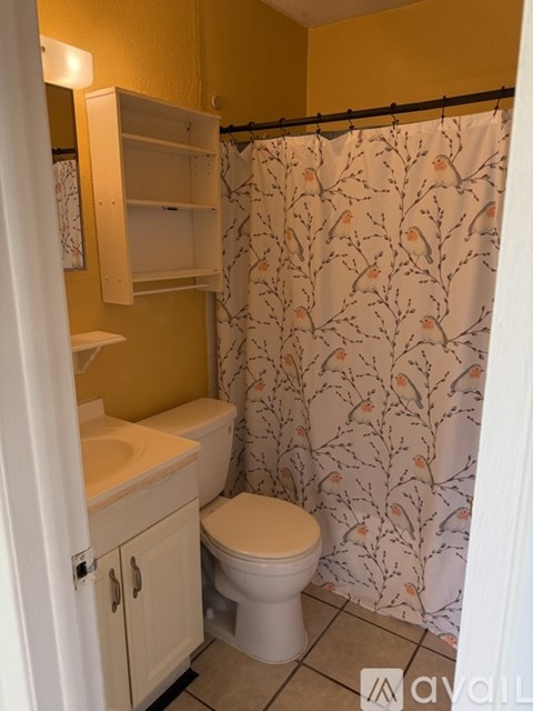 A bathroom with a toilet, sink, and shower curtain.