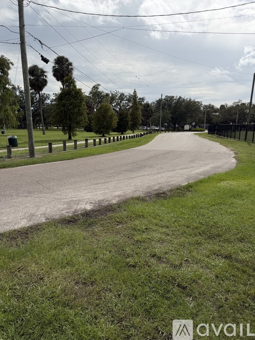 A road with grass on both sides and a fence on the right side.