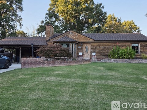 A house with a brown roof and a green lawn in front.