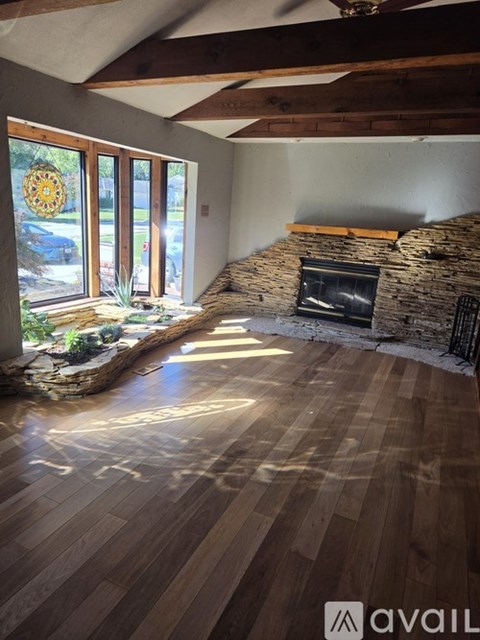 A room with wooden floors and a stone fireplace.