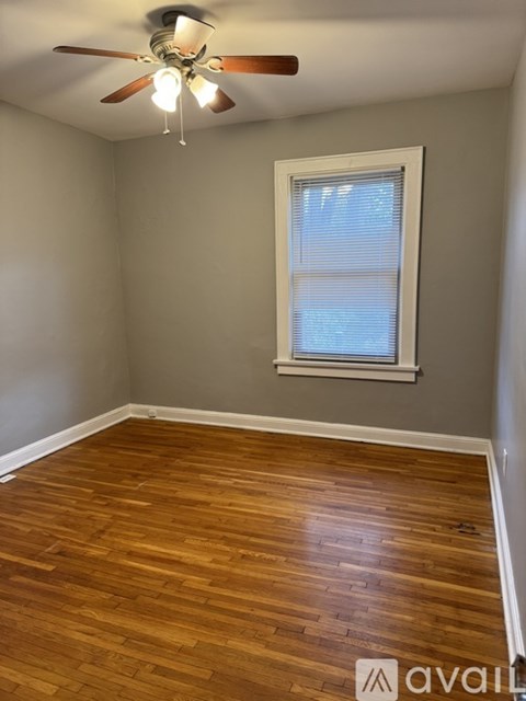A room with a ceiling fan and wooden flooring.