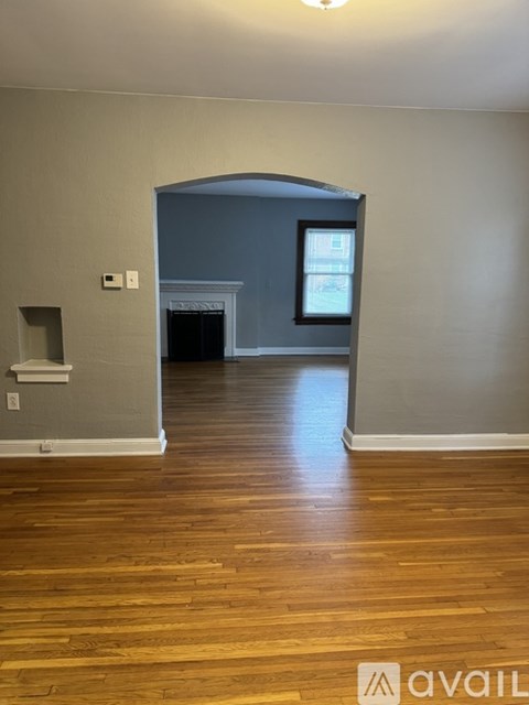 A room with wooden floors and a white wall with a window.
