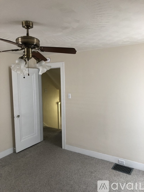 A room with a ceiling fan and a door.