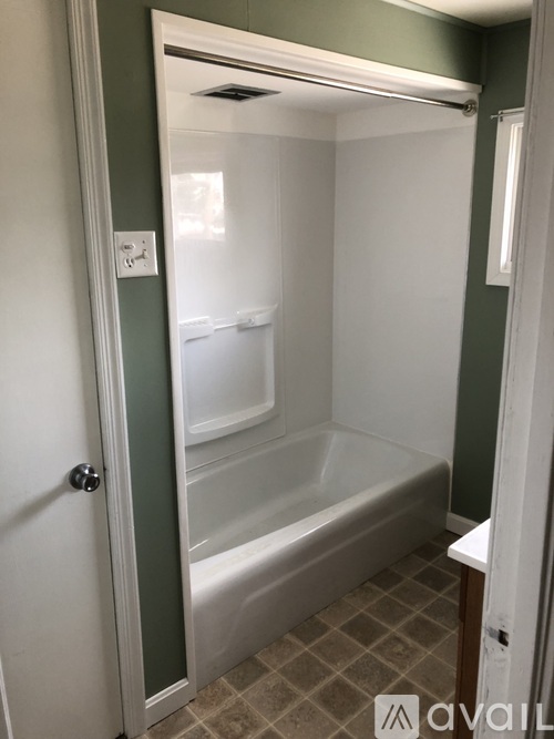 A bathroom with a white tub and a white door.