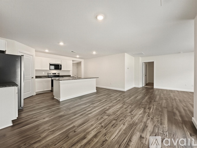 A spacious room with wooden flooring and white walls.