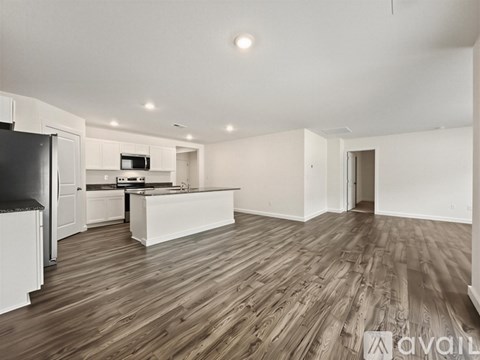 A spacious room with wooden flooring and white walls.