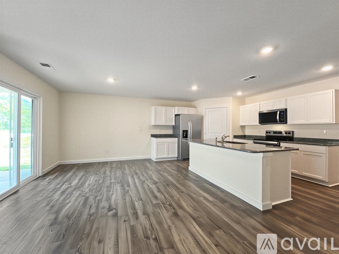 A spacious kitchen with white cabinets and a wooden floor.