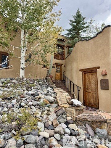 A brown house with a wooden door and a stone pathway leading to it.