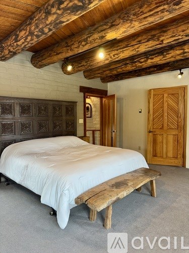 A bedroom with a bed and a wooden bench under a wooden ceiling.