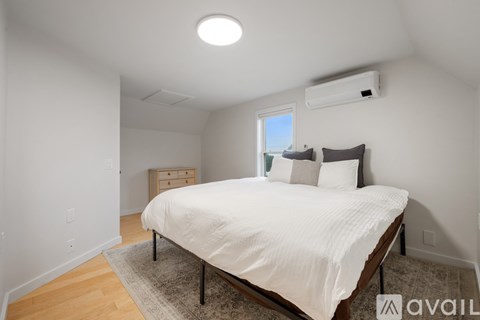 A bedroom with a bed, nightstand, and window.