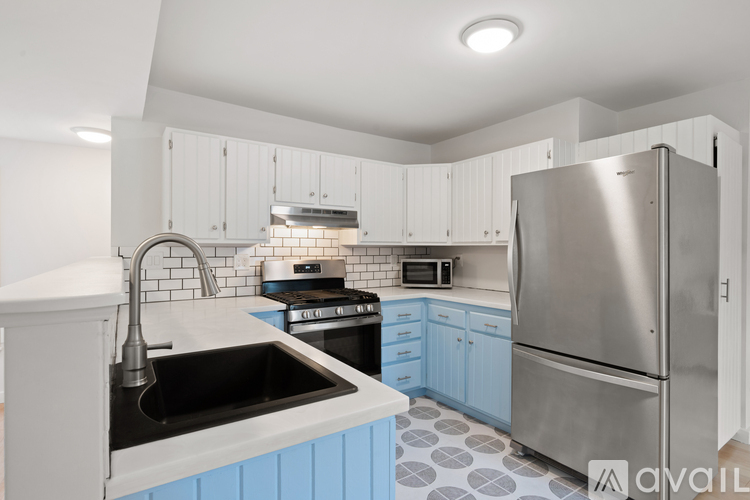 A kitchen with a stainless steel refrigerator and a black sink.