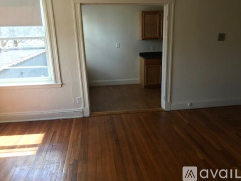 A room with wooden floors and a window with blinds.