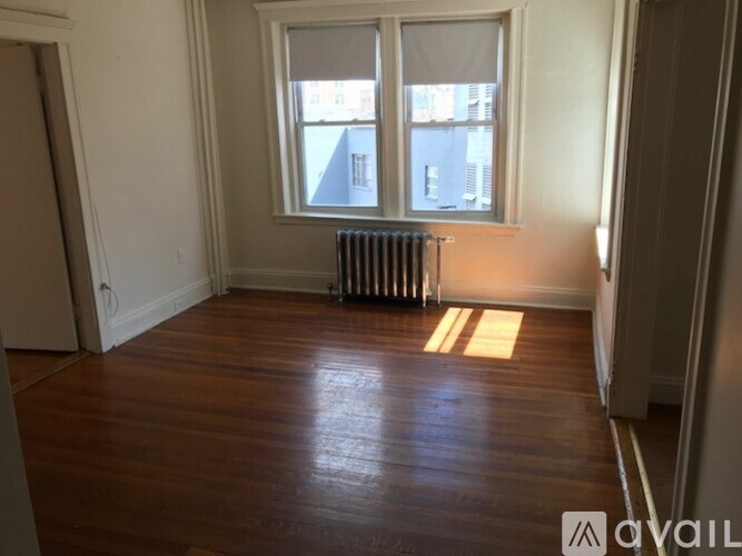 A room with wooden floors and a window with a view of a street.