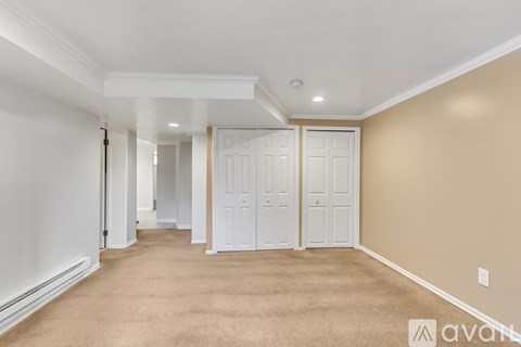 A long hallway with white doors and carpeted floors.
