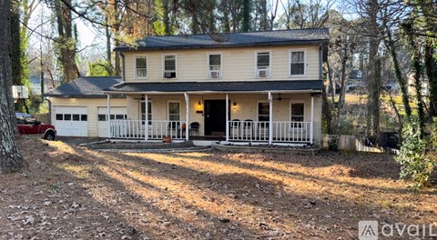 A two-story house with a white porch and a black roof.
