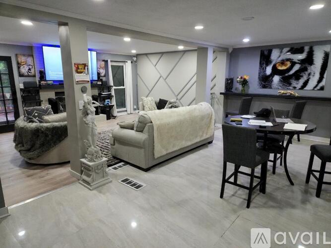 A living room with a white sofa, a black dining table, and a grey rug.