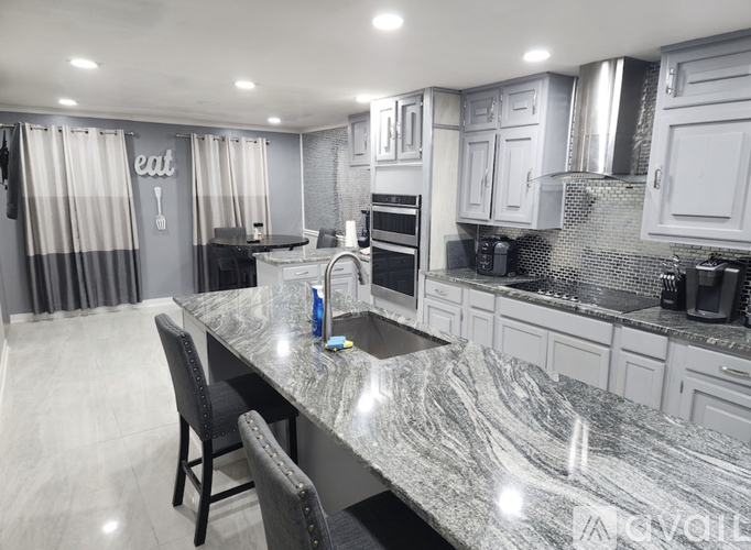 A kitchen with a marble countertop and a dining table with chairs.