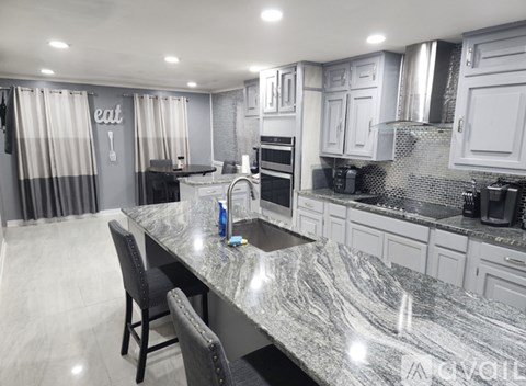 A kitchen with a marble countertop and a dining table with chairs.
