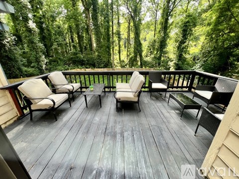 A wooden deck with chairs and a table in the middle of a forest.