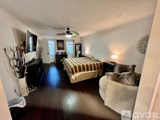 A bedroom with a bed, a couch, and a ceiling fan.
