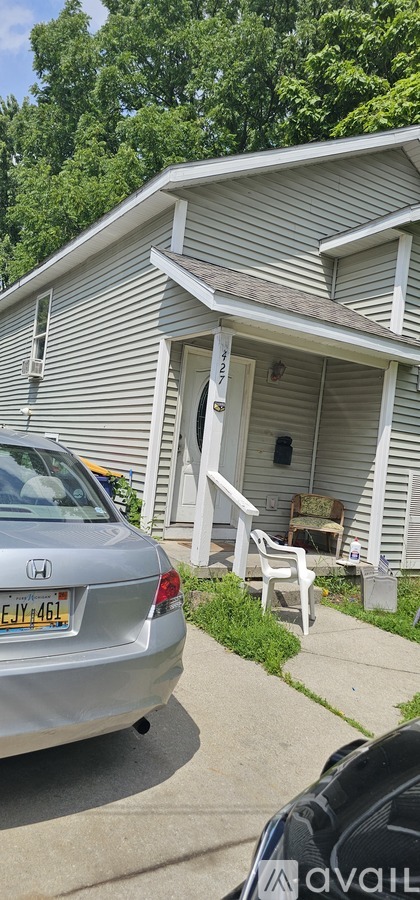 A silver car is parked in front of a house.
