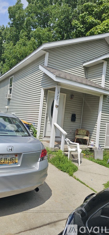 A silver car is parked in front of a house.
