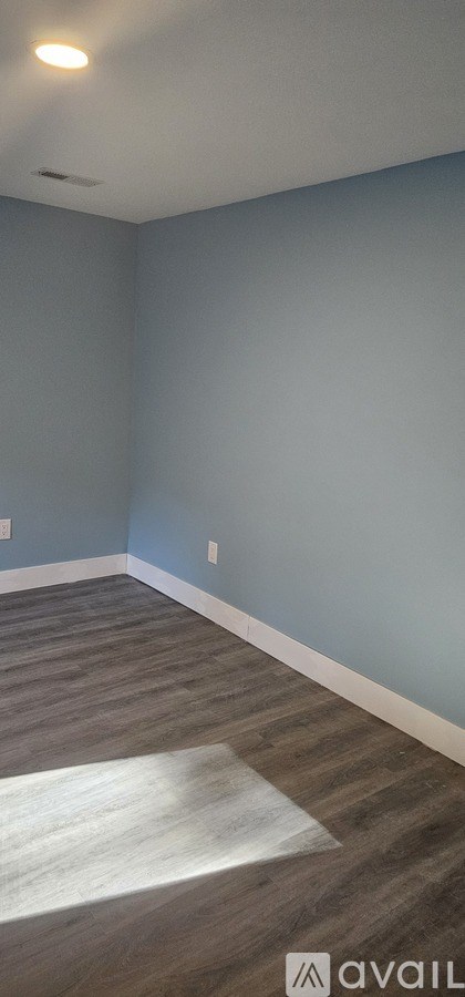 A room with a light blue wall and a wooden floor.