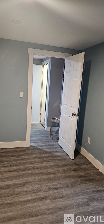 A room with a white door and a grey wall.
