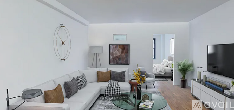 A living room with a white couch, a green rug, and a television.