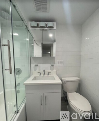 A white bathroom with a toilet, sink, and mirror.