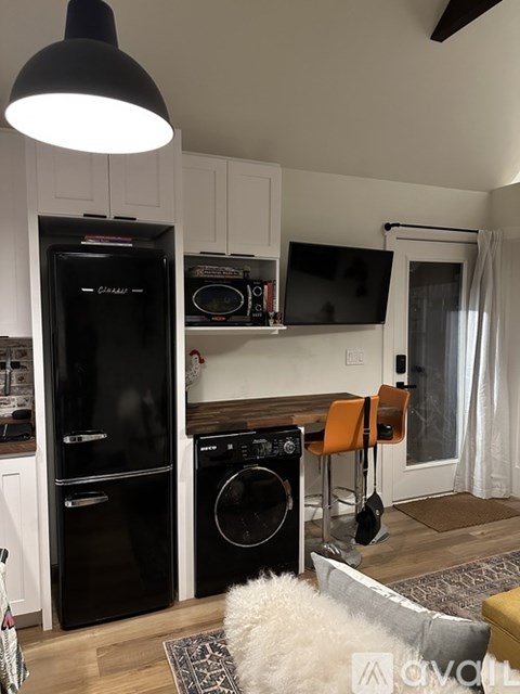 A black fridge and dishwasher in a kitchen with a white dog on the floor.