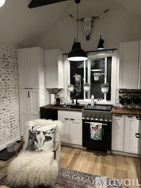 A kitchen with a white chair and a black stove.