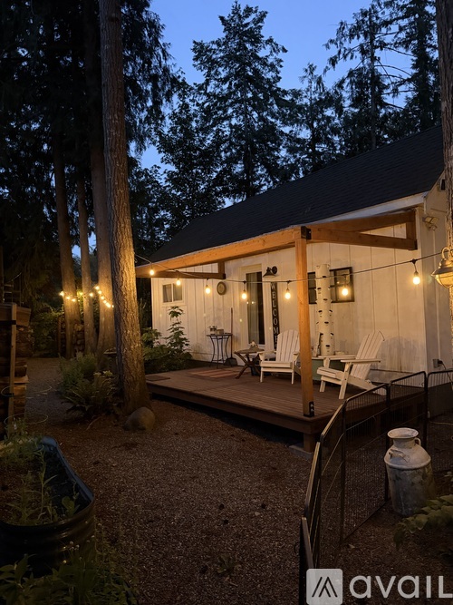 A cozy outdoor seating area with a lit patio and trees in the background.