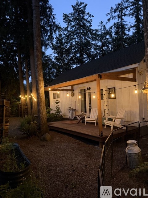 A cozy outdoor seating area with a lit patio and trees in the background.