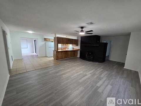A spacious living room with a fireplace and a ceiling fan.