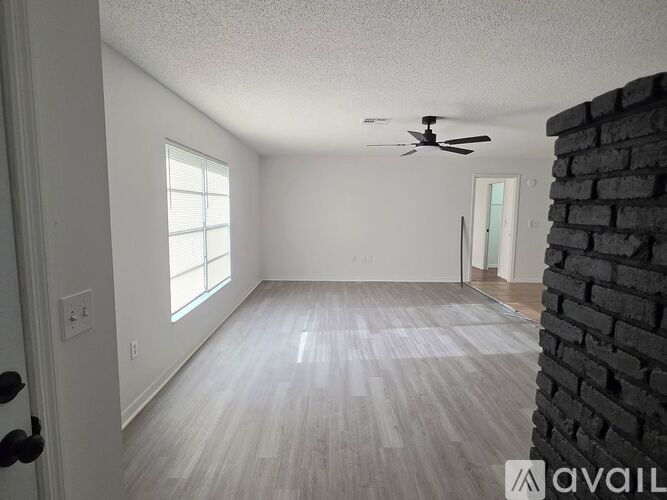 A room with a brick wall on the side and a ceiling fan.