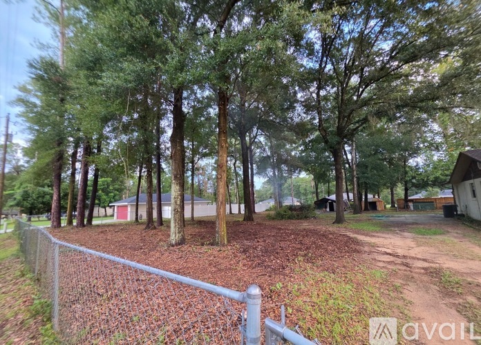 A fenced area with trees and a house in the background.