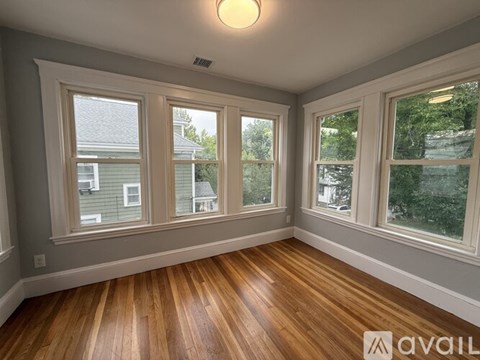 A room with wooden floors and three windows.